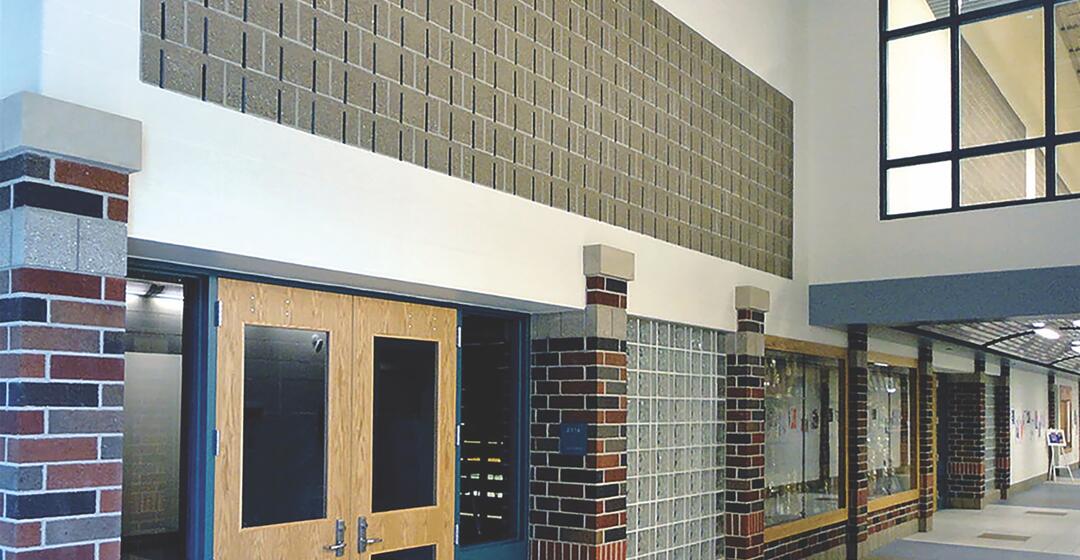 Soundblox sound absorbing structural masonry units used above double doors in a busy school foyer.